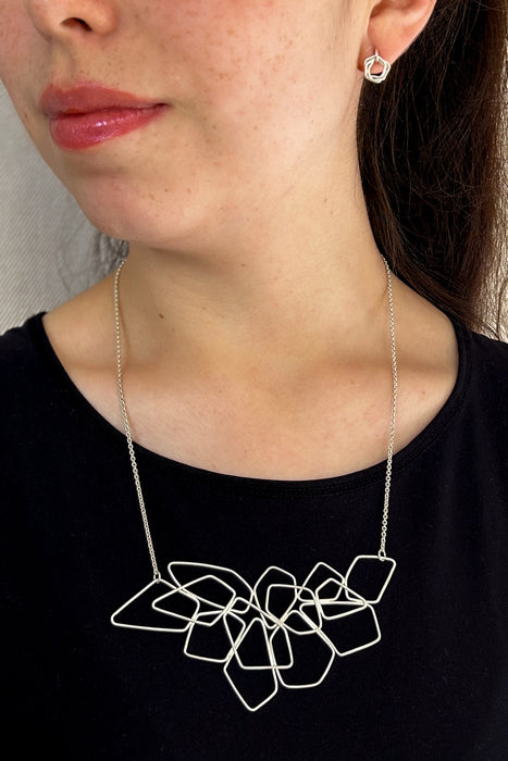 Das Collier „Fadenspiel“ ist ein elegantes Zusammenspiel aus ineinander fließenden Linien – zart, beweglich und doch kraftvoll in seiner Form. Jedes einzelne Element wird von Hand gebogen und zu einem harmonischen Gesamtbild verbunden.