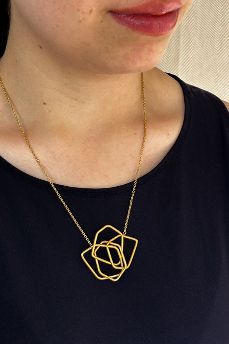 Das Collier Triade“ vereint unregelmäßig geformte, ineinander verschlungene Elemente zu einem harmonischen Mittelpunkt. Die klaren Linien und die sanft matte Oberfläche verleihen dem Schmuckstück eine ruhige, zugleich kraftvolle Ausstrahlung.