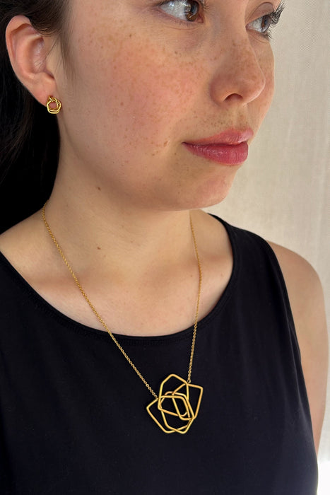 Das Collier Triade“ vereint unregelmäßig geformte, ineinander verschlungene Elemente zu einem harmonischen Mittelpunkt. Die klaren Linien und die sanft matte Oberfläche verleihen dem Schmuckstück eine ruhige, zugleich kraftvolle Ausstrahlung.