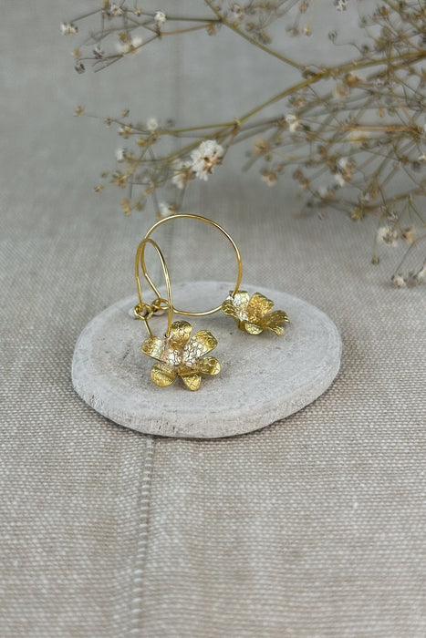 Zart und verspielt – die „Mini-Jacintos“ sind handgefertigte Ohrringe mit einer einzelnen, fein ziselierten Blüte, die sanft an einer Creole schwingt. Ihre schlichte Eleganz macht sie zu einem dezenten, aber besonderen Begleiter für jeden Tag.