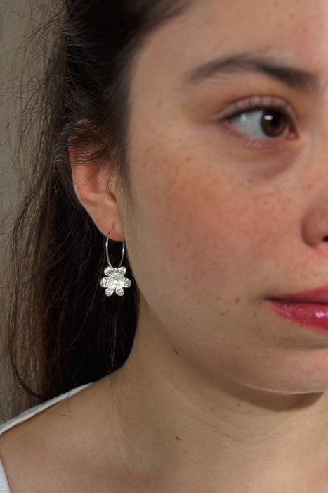 Zart und verspielt – die „Mini Jacintos“ sind handgefertigte Ohrringe mit einer einzelnen, fein ziselierten Blüte, die sanft an einer Creole schwingt. Ihre schlichte Eleganz macht sie zu einem dezenten, aber besonderen Begleiter für jeden Tag.