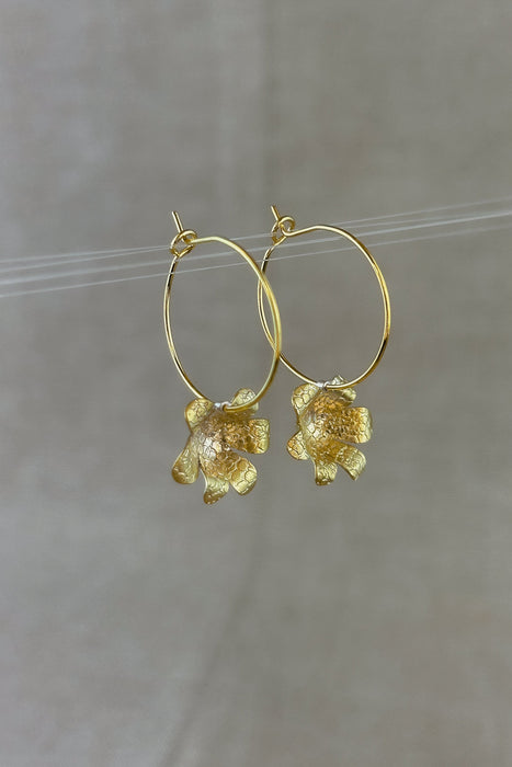 Zart und verspielt – die „Mini-Jacintos“ sind handgefertigte Ohrringe mit einer einzelnen, fein ziselierten Blüte, die sanft an einer Creole schwingt. Ihre schlichte Eleganz macht sie zu einem dezenten, aber besonderen Begleiter für jeden Tag.