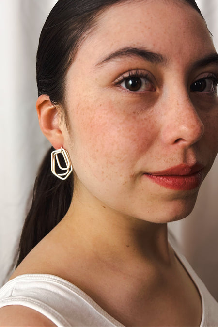 Zeitlos modern und doch handwerklich geprägt – diese geometrischen Ohrringe vereinen klare Linien mit warmer, goldener Ausstrahlung. Die ineinander verschlungenen Formen erzeugen Bewegung und Tiefe, während die matte Oberfläche einen sanften Glanz verleiht.