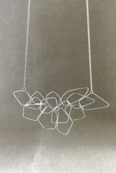 Das Collier „Fadenspiel“ ist ein elegantes Zusammenspiel aus ineinander fließenden Linien – zart, beweglich und doch kraftvoll in seiner Form. Jedes einzelne Element wird von Hand gebogen und zu einem harmonischen Gesamtbild verbunden.