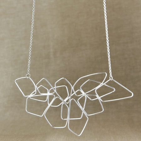 Das Collier „Fadenspiel“ ist ein elegantes Zusammenspiel aus ineinander fließenden Linien – zart, beweglich und doch kraftvoll in seiner Form. Jedes einzelne Element wird von Hand gebogen und zu einem harmonischen Gesamtbild verbunden.