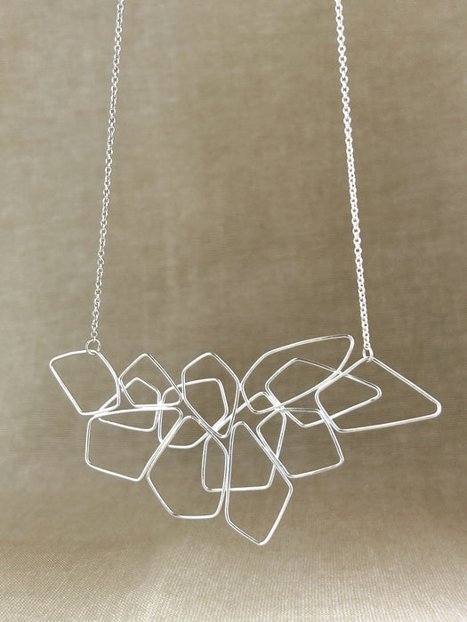 Das Collier „Fadenspiel“ ist ein elegantes Zusammenspiel aus ineinander fließenden Linien – zart, beweglich und doch kraftvoll in seiner Form. Jedes einzelne Element wird von Hand gebogen und zu einem harmonischen Gesamtbild verbunden.