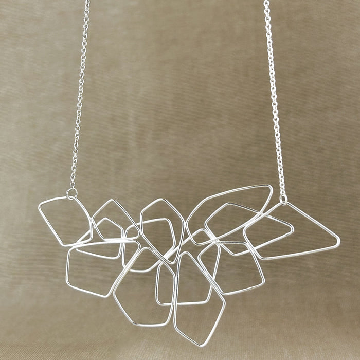Das Collier „Fadenspiel“ ist ein elegantes Zusammenspiel aus ineinander fließenden Linien – zart, beweglich und doch kraftvoll in seiner Form. Jedes einzelne Element wird von Hand gebogen und zu einem harmonischen Gesamtbild verbunden.