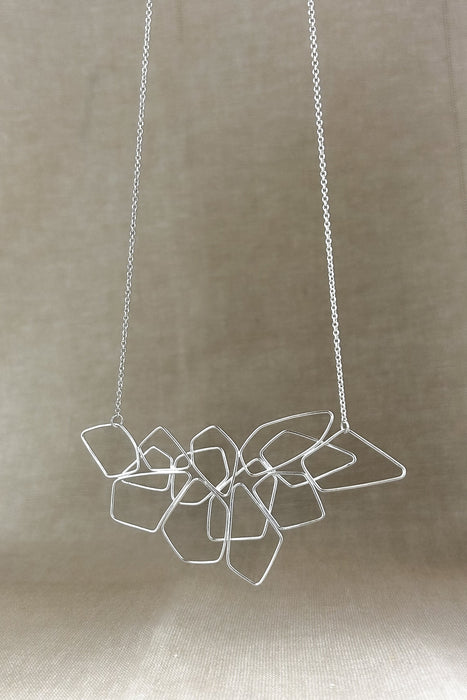 Das Collier „Fadenspiel“ ist ein elegantes Zusammenspiel aus ineinander fließenden Linien – zart, beweglich und doch kraftvoll in seiner Form. Jedes einzelne Element wird von Hand gebogen und zu einem harmonischen Gesamtbild verbunden.