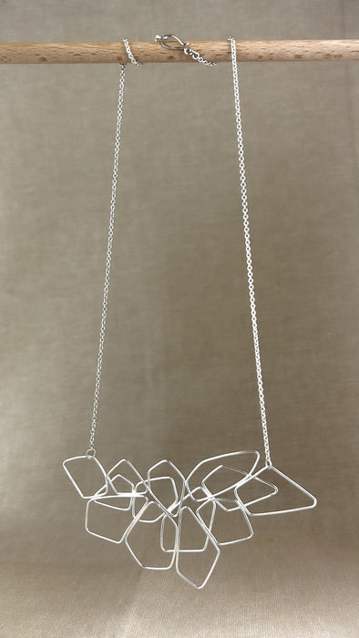 Das Collier „Fadenspiel“ ist ein elegantes Zusammenspiel aus ineinander fließenden Linien – zart, beweglich und doch kraftvoll in seiner Form. Jedes einzelne Element wird von Hand gebogen und zu einem harmonischen Gesamtbild verbunden.