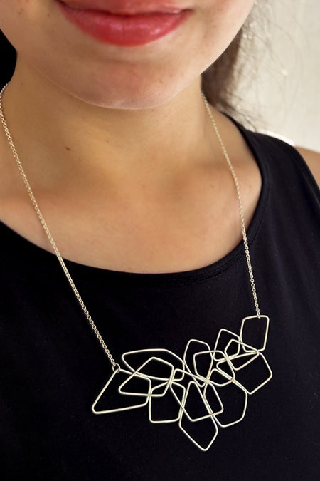 Das Collier „Fadenspiel“ ist ein elegantes Zusammenspiel aus ineinander fließenden Linien – zart, beweglich und doch kraftvoll in seiner Form. Jedes einzelne Element wird von Hand gebogen und zu einem harmonischen Gesamtbild verbunden.