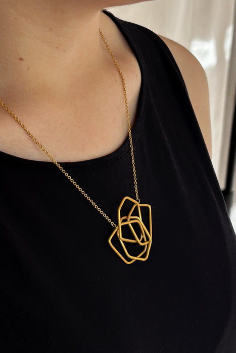 Das Collier Triade“ vereint unregelmäßig geformte, ineinander verschlungene Elemente zu einem harmonischen Mittelpunkt. Die klaren Linien und die sanft matte Oberfläche verleihen dem Schmuckstück eine ruhige, zugleich kraftvolle Ausstrahlung.