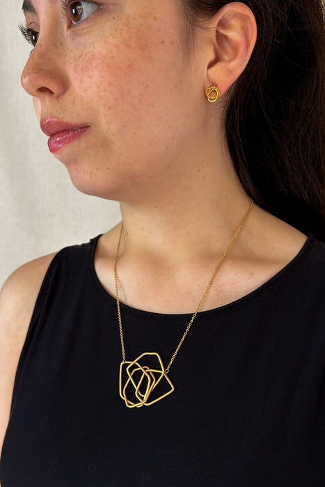 Das Collier Triade“ vereint unregelmäßig geformte, ineinander verschlungene Elemente zu einem harmonischen Mittelpunkt. Die klaren Linien und die sanft matte Oberfläche verleihen dem Schmuckstück eine ruhige, zugleich kraftvolle Ausstrahlung.