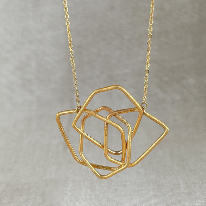 Das Collier Triade“ vereint unregelmäßig geformte, ineinander verschlungene Elemente zu einem harmonischen Mittelpunkt. Die klaren Linien und die sanft matte Oberfläche verleihen dem Schmuckstück eine ruhige, zugleich kraftvolle Ausstrahlung.