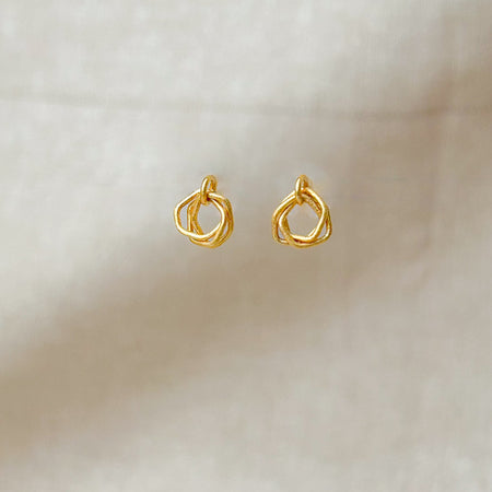 Zeitlos modern und doch handwerklich geprägt – diese geometrischen Ohrringe vereinen klare Linien mit warmer, goldener Ausstrahlung. Die ineinander verschlungenen Formen erzeugen Bewegung und Tiefe, während die matte Oberfläche einen sanften Glanz verleiht.