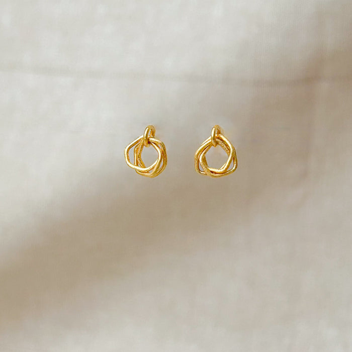 Zeitlos modern und doch handwerklich geprägt – diese geometrischen Ohrringe vereinen klare Linien mit warmer, goldener Ausstrahlung. Die ineinander verschlungenen Formen erzeugen Bewegung und Tiefe, während die matte Oberfläche einen sanften Glanz verleiht.