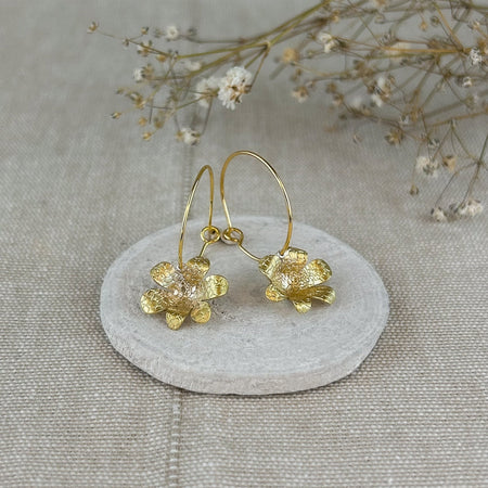 Zart und verspielt – die „Mini-Jacintos“ sind handgefertigte Ohrringe mit einer einzelnen, fein ziselierten Blüte, die sanft an einer Creole schwingt. Ihre schlichte Eleganz macht sie zu einem dezenten, aber besonderen Begleiter für jeden Tag.