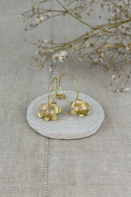 Zart und verspielt – die „Mini-Jacintos“ sind handgefertigte Ohrringe mit einer einzelnen, fein ziselierten Blüte, die sanft an einer Creole schwingt. Ihre schlichte Eleganz macht sie zu einem dezenten, aber besonderen Begleiter für jeden Tag.