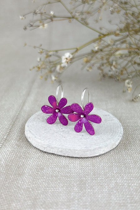 Die „Silvestres“ sind leichte, handgefertigte Ohrringe mit einer zarten Blüte, die dezent schwingt und jedem Look eine natürliche, frische Note verleiht. Die Blume wird aus Silber oder Messing gefertigt und emailliert, sodass verschiedene Farbvarianten möglich sind. Die Ohrhaken bestehen immer aus 925er Silber – angenehm zu tragen und hochwertig verarbeitet, ganz in traditioneller Handarbeit.