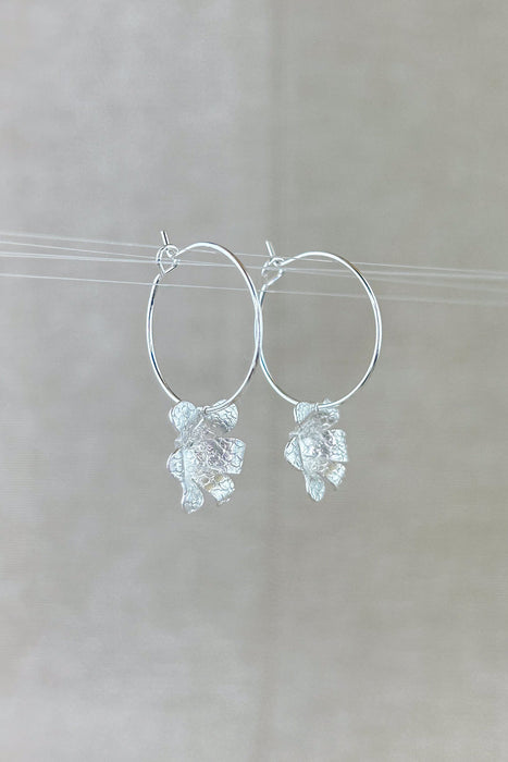 Zart und verspielt – die „Mini-Jacintos“ sind handgefertigte Ohrringe mit einer einzelnen, fein ziselierten Blüte, die sanft an einer Creole schwingt. Ihre schlichte Eleganz macht sie zu einem dezenten, aber besonderen Begleiter für jeden Tag.