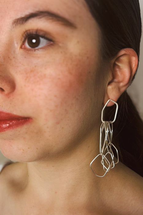 Leicht, verspielt und voller Bewegung – die Ohrringe „Fadenspiel“ verbinden zarte Linien zu einem kunstvollen Ganzen. Feine, unregelmäßig geformte Elemente hängen in fließender Bewegung zusammen und erzeugen beim Tragen ein lebendiges Spiel von Licht und Form.