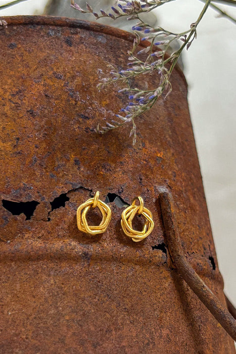 Mini Triade mit Hintergrund Schmuck mit Charakter. Zeitlos modern und doch handwerklich geprägt – diese geometrischen Ohrringe vereinen klare Linien mit warmer, goldener Ausstrahlung. Die ineinander verschlungenen Formen erzeugen Bewegung und Tiefe, während die matte Oberfläche einen sanften Glanz verleiht.