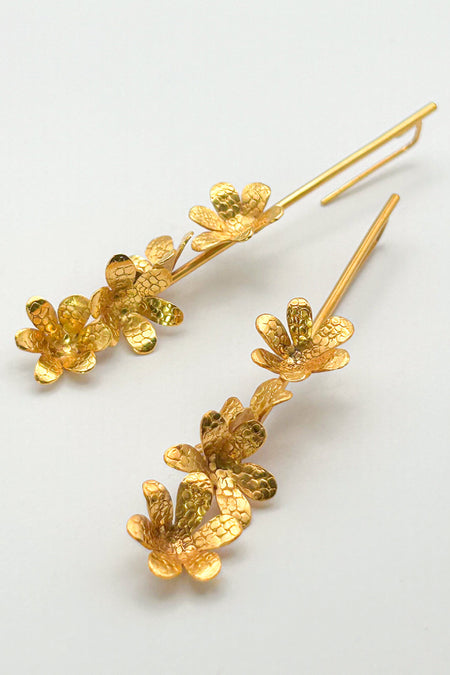 Die Ohrringe „Jacintos“ verbinden schlichte Eleganz mit handwerklicher Präzision. Mehrere kleine, von Hand geformte Blüten hängen aneinander und erzeugen bei jeder Bewegung ein feines Spiel aus Glanz und Struktur.