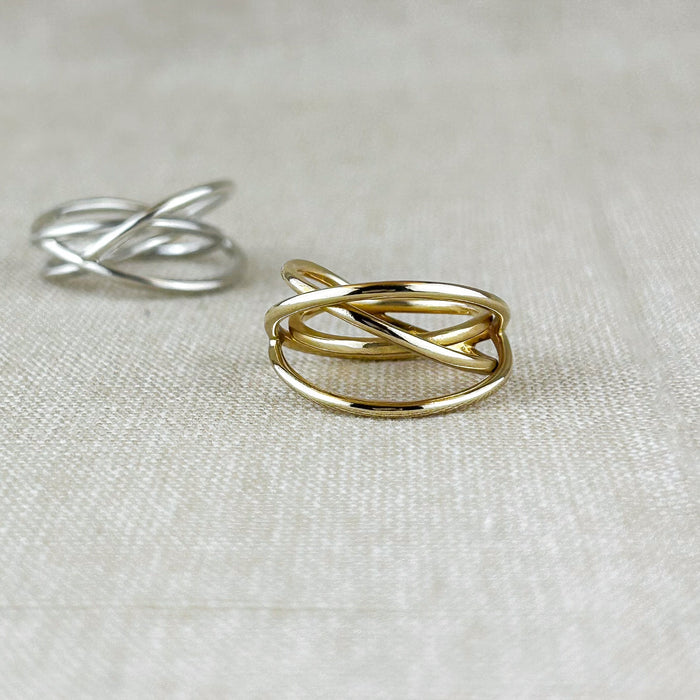 Ein Ring voller Bewegung und Leichtigkeit. Dieses außergewöhnliche Design aus 100% recyceltem Silber 925 oder 100% recyceltem 14 Karat Gold spielt mit fließenden, sich kreuzenden Linien, die an ein Hula Hoop in Bewegung erinnern. Die glänzende Oberfläche reflektiert das Licht sanft und betont die dynamische Form – ein Schmuckstück, das gleichzeitig modern und klassisch wirkt.