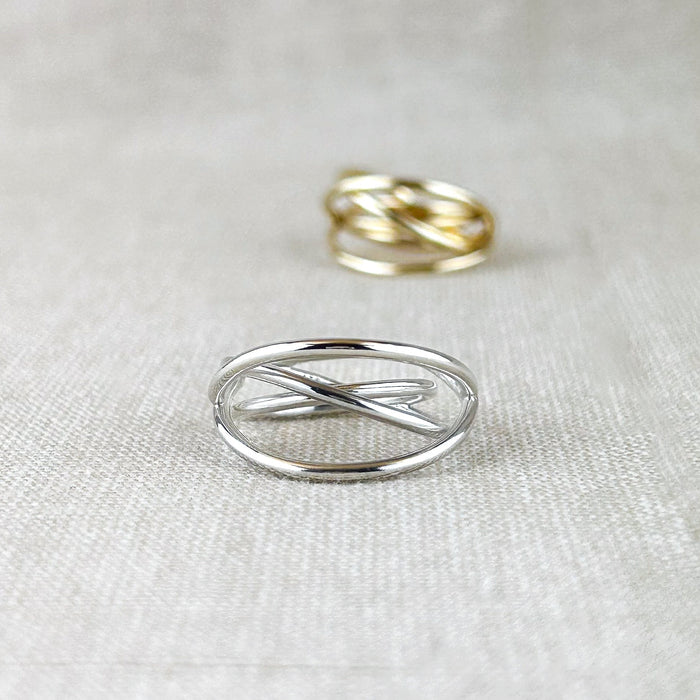 Ein Ring voller Bewegung und Leichtigkeit. Dieses außergewöhnliche Design aus 100% recyceltem Silber 925 oder 100% recyceltem 14 Karat Gold spielt mit fließenden, sich kreuzenden Linien, die an ein Hula Hoop in Bewegung erinnern. Die glänzende Oberfläche reflektiert das Licht sanft und betont die dynamische Form – ein Schmuckstück, das gleichzeitig modern und klassisch wirkt.