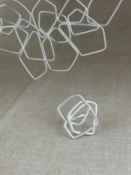 Das Collier „Fadenspiel“ ist ein elegantes Zusammenspiel aus ineinander fließenden Linien – zart, beweglich und doch kraftvoll in seiner Form. Jedes einzelne Element wird von Hand gebogen und zu einem harmonischen Gesamtbild verbunden.